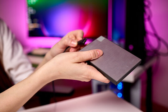 Closeup of external hard drive being connected to desktop computer. Modern workspace setting with data migration between external hard drive and desktop computer