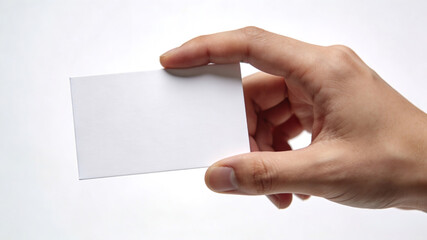 Obraz premium Close up of a hand holding a blank white business card against a white background, mockup for branding and corporate identity.