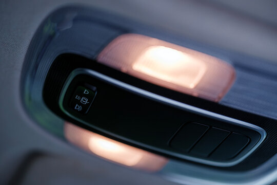 Interior cabin ceiling view of a modern hyundai i20 showing the illuminated overhead reading lamps emitting warm yellow light next to the interior switch mechanism