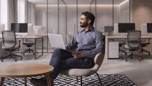 Young thoughtful bearded smart indian professional business man executive looking away sitting on chair in modern office lobby using laptop, thinking of new ideas, planning project, working online.