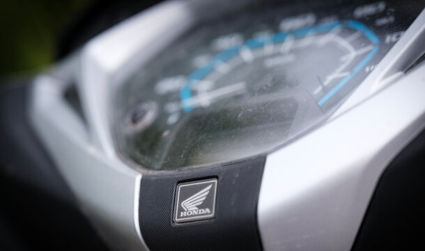 Close up view of a modern motorcycle dashboard featuring an analog speedometer and digital display with the iconic Honda emblem visible below the instrument cluster