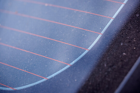 Extreme botanical like abstract macro capturing the delicate edge structure of the rear glass defogger grid contrasting sharply against deeply soiled dark exterior vehicle surfaces