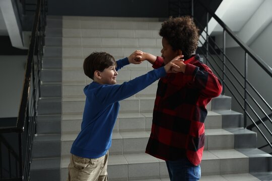 Bullying. Boy fighting with his African American classmate in school