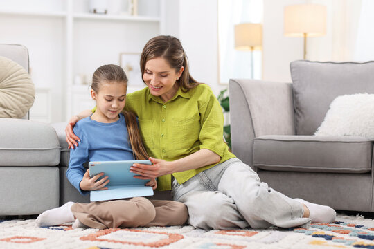 Mother and her daughter using tablet at home