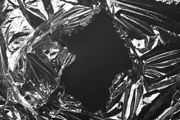 Fototapeta premium Torn plastic wrap on black background, top view. Space for text
