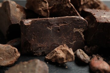 Fototapeta premium Natural chocolate chunks and cocoa beans on grey table, closeup