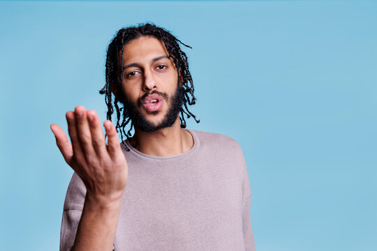 Handsome arab man sending air kiss and making romantic affection gesture portrait. Young adult attractive brunette person expressing love and flirting while looking at camera