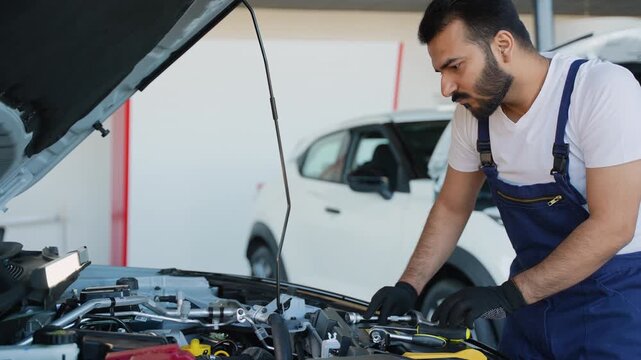 Professional Indian auto mechanic repairing a car engine in a service station