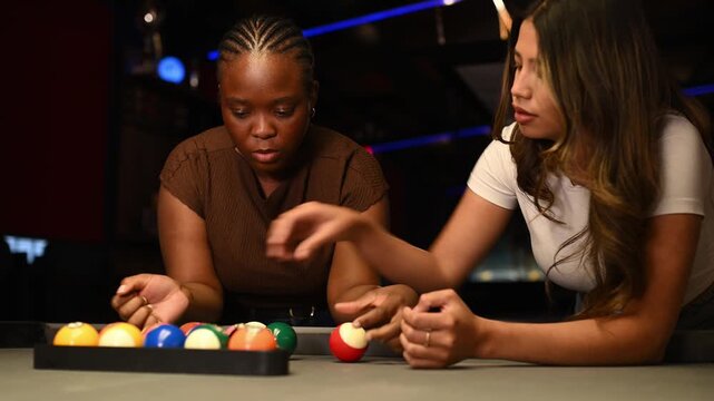 Diverse friends learning to play billiards together while having fun in a pub on a girls night out