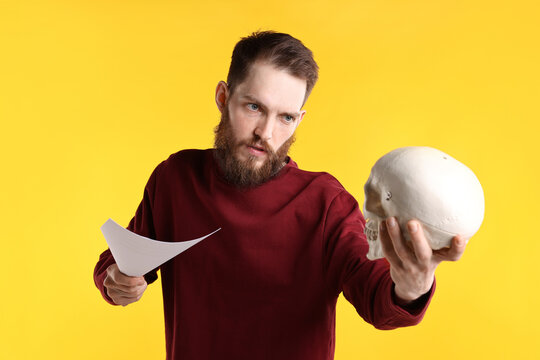 Professional actor with skull and script performing on yellow background
