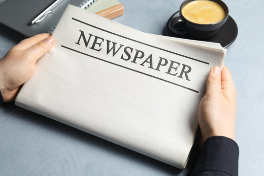 Man with newspaper at grey table, closeup