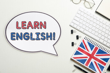 Obraz premium Speech balloon with phrase Learn English, stationery and computer keyboard on table, top view. Language course poster