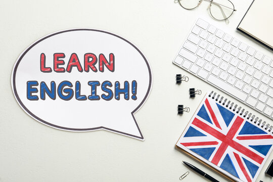 Speech balloon with phrase Learn English, stationery and computer keyboard on table, top view. Language course poster