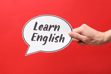 Obraz premium Woman holding paper speech balloon with phrase Learn English against red background, closeup. Language course poster