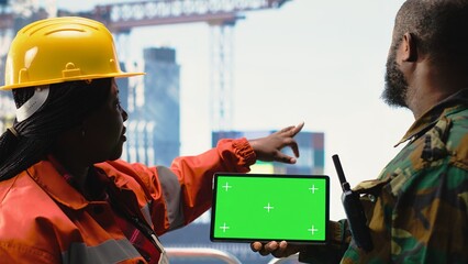 Chroma key tablet used by soldier on offshore platform deck talking with technician. African american naval unit guards drilling rig against terrorist threat using green screen mockup device © DC Studio