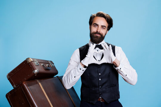 Joyful bellboy does heart shape sign on camera, indicating romantic feelings and flirting while he wears suit and tie. Lovely doorman showing romance symbol for love, sincere emotions.