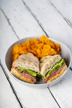  ham and cheddar focaccia sandwich with a bowl of sweet potato chips