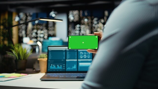 African american man working with green screen on mobile phone in modern space, checking online insights in strategy room. Male general manager handling business administration.