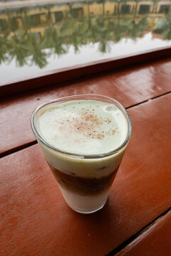a Vietnamese coconut coffee, resting on a polished reddish-brown wooden table