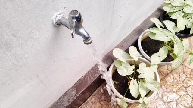 Man hand turning a chrome water tap in slow motion to start a flow in a home garden