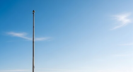 Obraz premium A slender metal pole against a clear, expansive blue sky, evoking a sense of space and tranquility