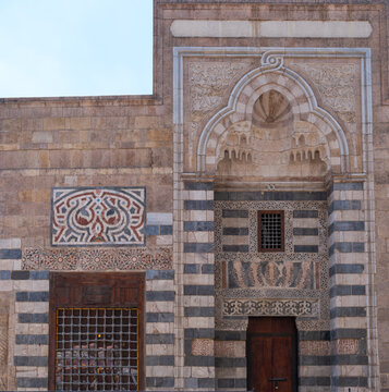 View of the intricate stone carvings and ablaq masonry on the facade of the Zawya and Sabil of Sultan Faraj Ibn Barquq in Cairo, Egypt.