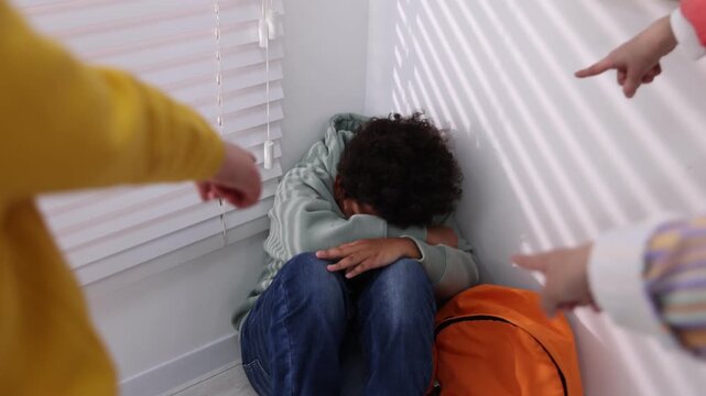 African American boy getting bullied by his classmates in classroom