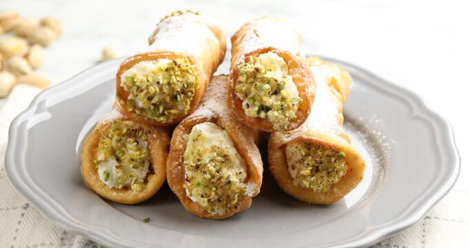 Delicious cannoli with cheese, pistachios and powdered sugar on table, closeup