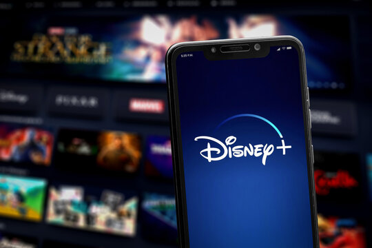 Cali, Colombia - December 5, 2023: Smartphone showing Disney+ logo against blurred TV app interface.