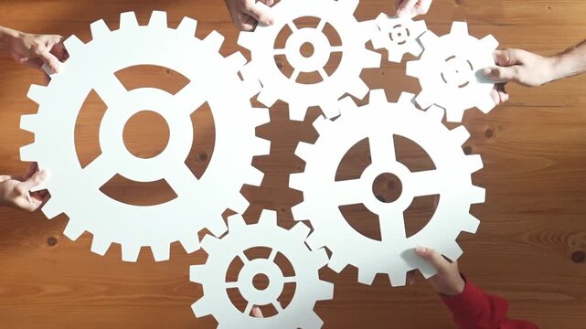 Top view of business people gathering white gear together at meeting table. Group start up team in casual cloth working together connecting cog together. Cooperate, teamwork,togetherness. Convocation.