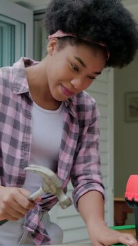 Vertical video: Placing toolbox, woman in shirt pulling fabric nailing frame on porch, copy space