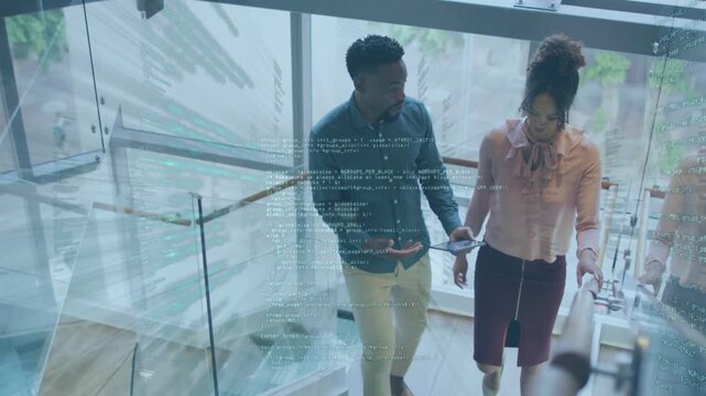 Man and woman walking down glass staircase while man tapping tablet and reviewing tech code overlay