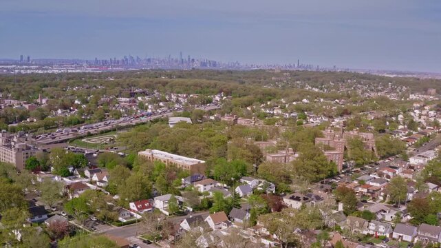 aerial pan across lush Staten Island neighborhoods. Residential streets and green trees lead the eye to the iconic New York City skyline.