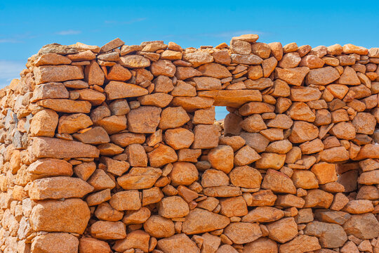 View of a traditional dry stone wall in the Canary Islands with a small square opening under a clear blue sky in Lanzarote, Canarias, Spain.