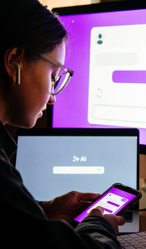 Young woman writing AI promt in a modern office.