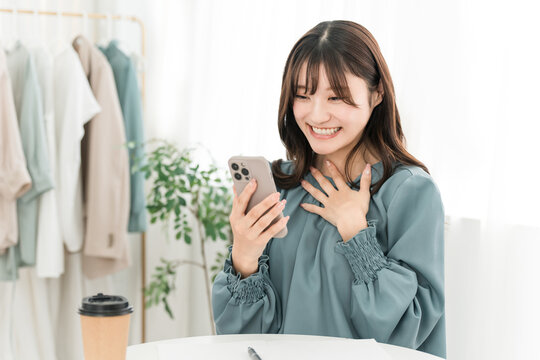 A woman smiling happily and joyfully while looking at her smartphone.