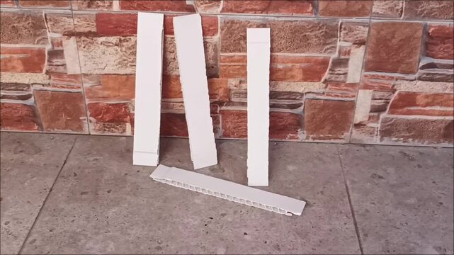 Close up of white hollow plastic strips and PVC extrusion profiles on stone floor for industrial build project.
