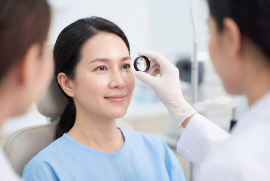 Ophthalmologist examining female patient eye with medical lens