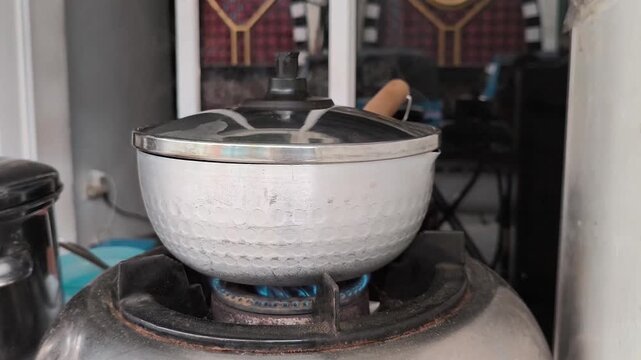 Aluminum Pot Boiling on Gas Stove with Blue Flame
