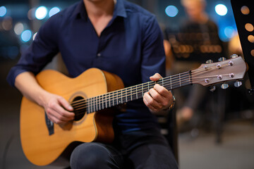 Obraz premium Man Playing Acoustic Guitar During A Live Performance With Out Of Focus Background Lights