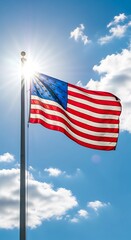 Obraz premium American flag waving in bright blue sky with white clouds on sunny day