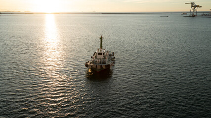 Obraz premium Tugboat sailing on the golden sparkling sea during sunset harbor view