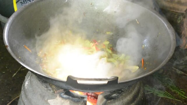 Close-up of cooking spicy Indonesian stir-fried noodles with fresh ingredients in a pan