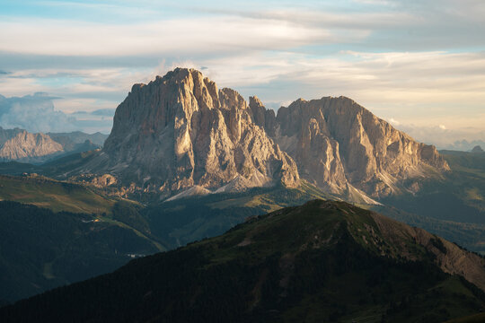 View of the Langkofel mountain group with its jagged peaks and green alpine slopes under a soft sunset sky in the Dolomites Trentino-South Tyrol, Italy.