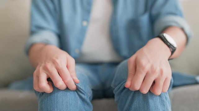 Closeup legs shaking in a guy in blue jeans. Uncontrollable leg shaking. Severe stress in a guy. A man is worried while sitting on a sofa. Health problems and sickness