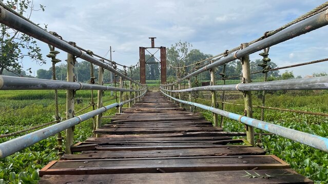 Rustic Suspension Bridge Over Water with Wooden Structure and Scenic Natural Landscape View