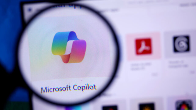 Microsoft copilot logo on a computer screen through a magnifying glass