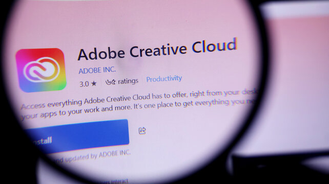 Magnifying glass showing adobe creative cloud app on screen closeup