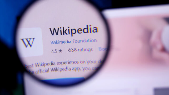 Magnifying glass showing wikipedia app on a mobile device screen closeup