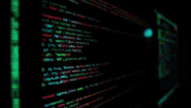 Dark blurred computer screen with colorful programming code and cyber atmosphere